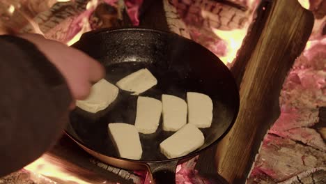 thick slices of halloumi cheese tossed into hot iron pan on camp fire