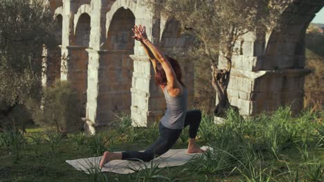 una instructora de yoga en forma realiza una pose de yoga dentro de la naturaleza en el antiguo acueducto