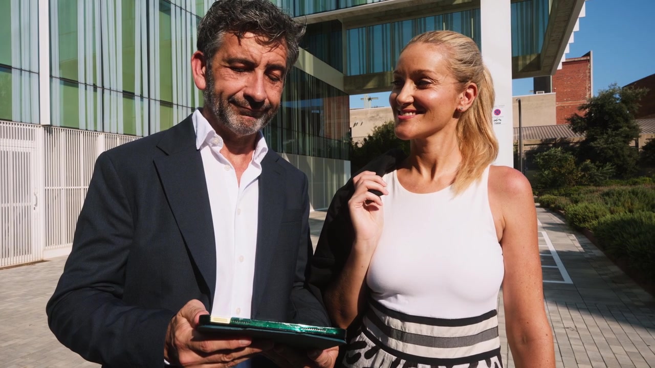 Profissionais de Negócios Discutindo Trabalho em Tablet Fora de Edifício de Escritórios Moderno