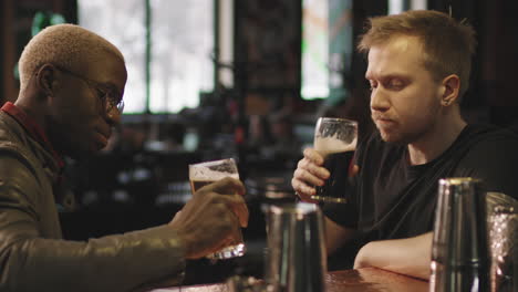multi-ethnic male friends drinking beer at bar