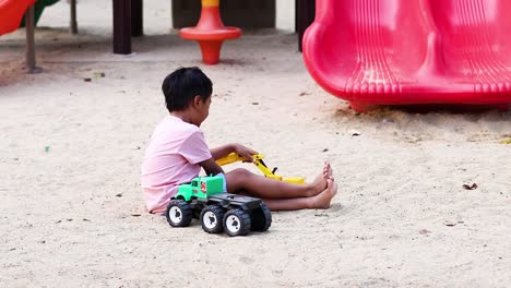 boy playing with toy truck in sandbox at a playground