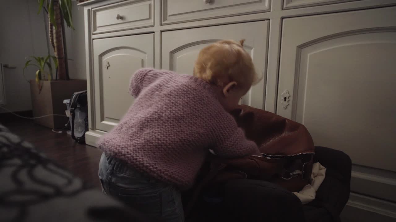 거실에 있는 가방에서 장난감을 꺼내는 아기