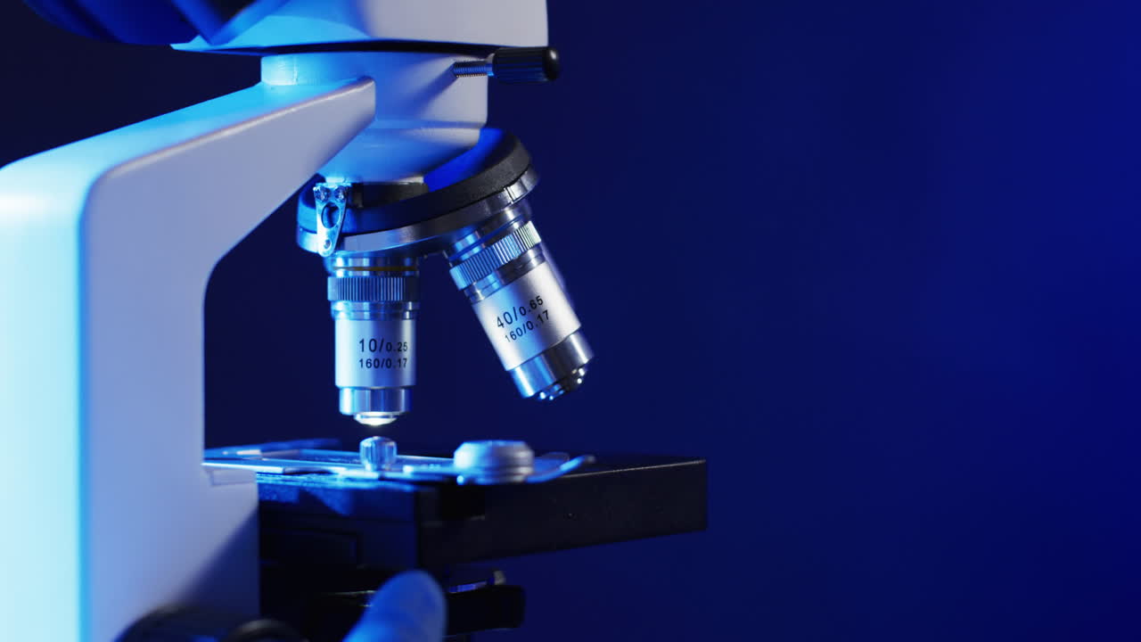 Video of close up of laboratory microscope with copy space on blue background