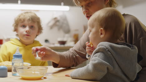 mother feeding baby son at home