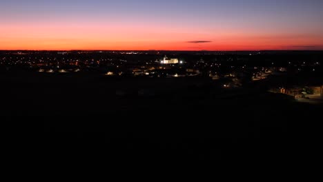 Paisaje-Aéreo-De-La-Ciudad-De-Las-Residencias-Iluminadas-Por-Las-Luces-De-La-Calle-Al-Atardecer