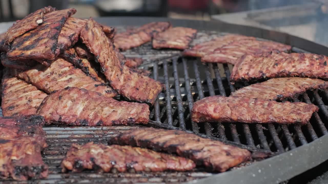 Roasted pork ribs are grilled on charcoal big spinning grill. Street food festival