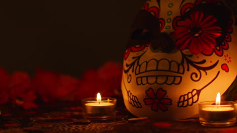 still life of decorated skull mask surrounded by candles and flowers celebrating mexican holiday of dia de muertos or day of the dead against dark background 2