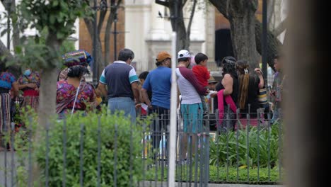 antigua guatemala indigenous people gather in the town's main plaza to sell handcrafted souvenirs to tourists during the daytime as native woman with colorful fabrics walks along-handheld slow motion