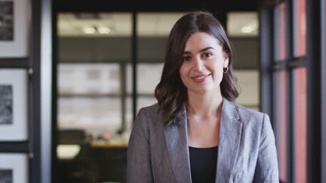 Dark-haired,-confident-young-businesswoman-crossing-arms-and-smiling-to-camera,-close-up