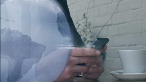 animation of globe icon against mid section of businessman using laptop at a cafe