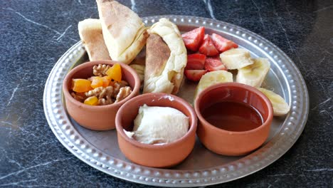 desayuno turco con pan, fresas, plátanos, miel, mantequilla, albaricoque y nueces