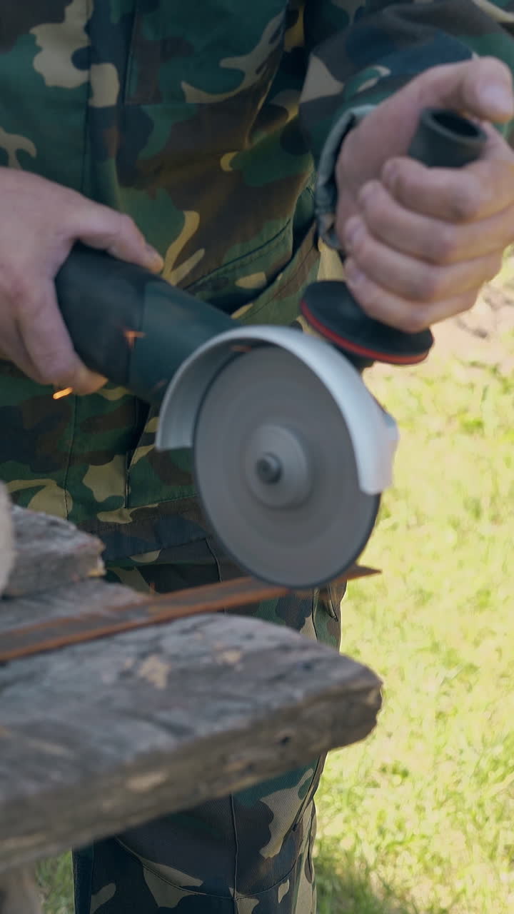 Person in Camouflage Working with Grinder on Metal