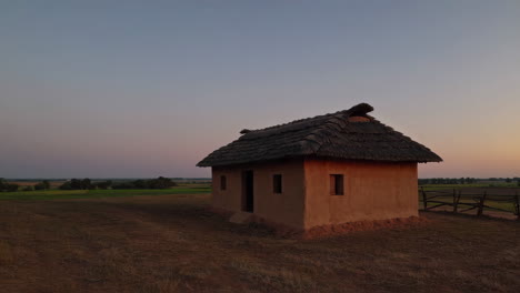 ancient mud house in a field at sunset