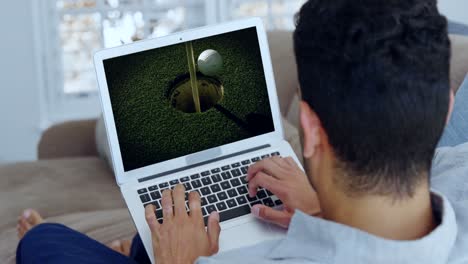 hombre viendo golf en el portátil en la sala de estar