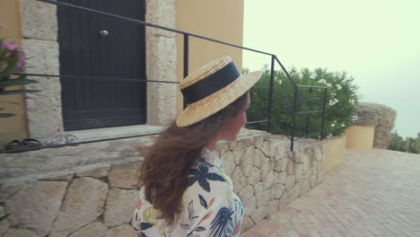 una hermosa mujer con un sombrero de paja camina a lo largo de la playa