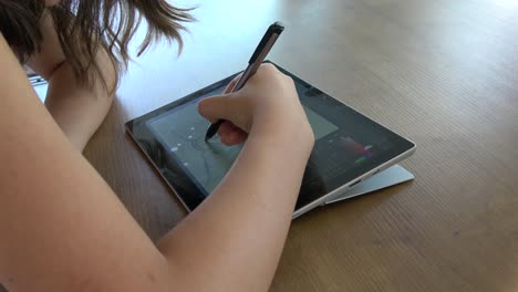 niña dibujando en una tableta gráfica, por encima del hombro