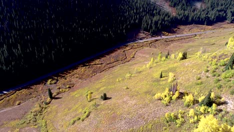 Morning-sun-over-a-valley-where-a-road-winds-through-aspens-and-pines