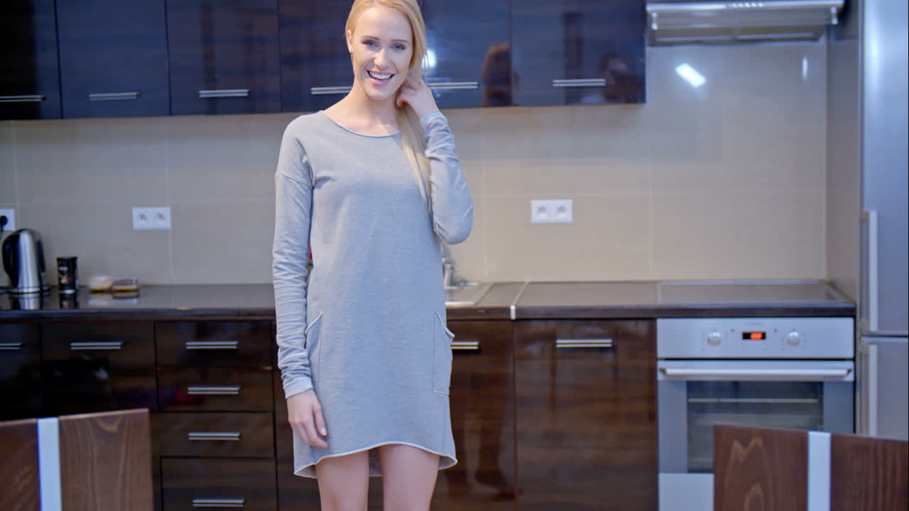 Donna bionda sorridente che posa in cucina