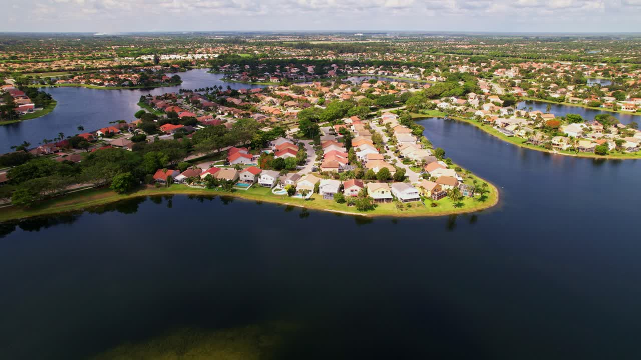 Crane down drone shot of residential area, real estate and a lake during the day in West Palm Beach, Florida, USA