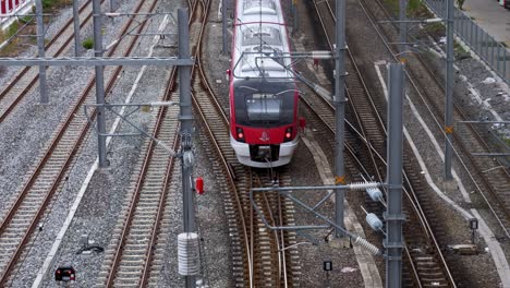 View-from-above-of-an-inter-provincial-train-leaving-the-train-station,-moving-at-the-centre-forward-of-the-frame-in-Bangkok,-Thailand