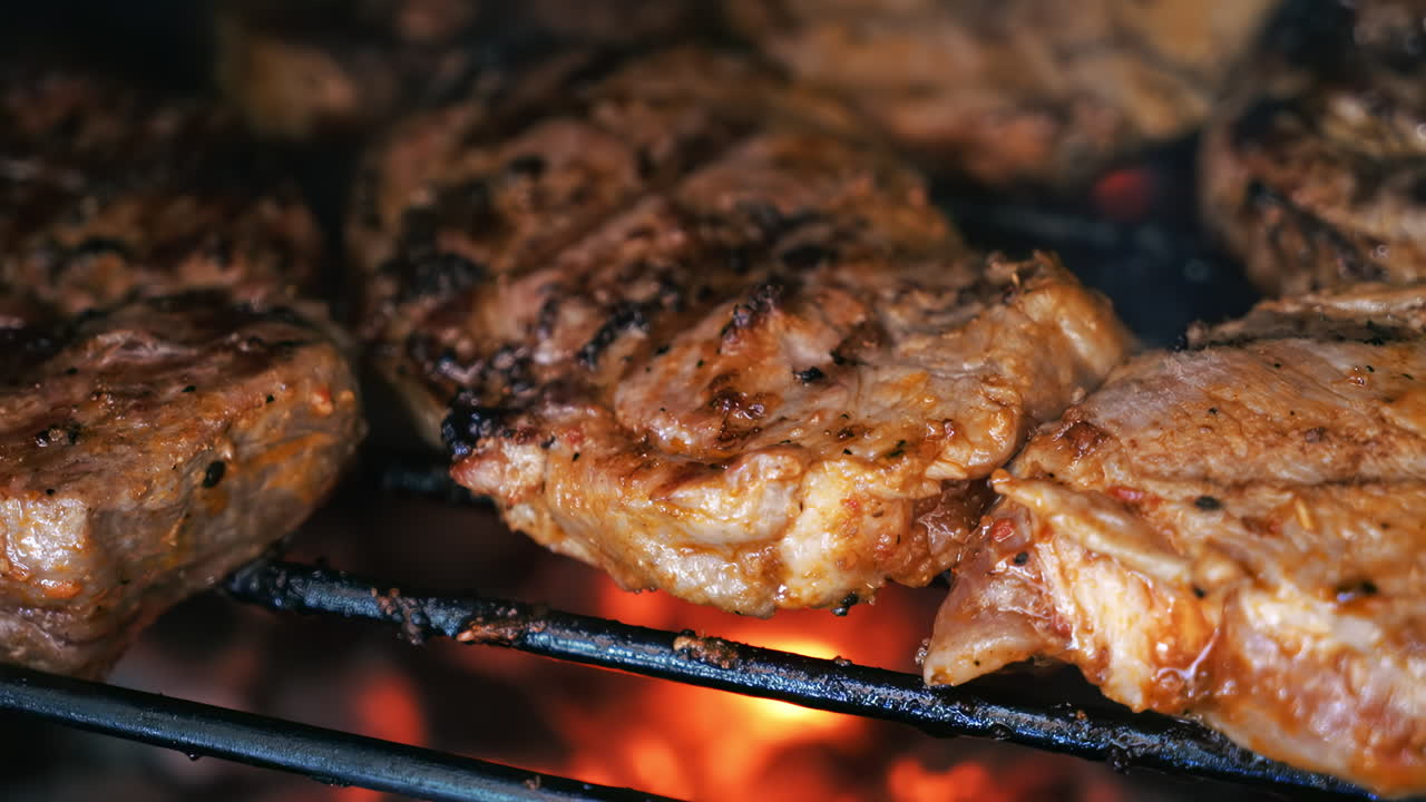Roasting juicy meat steak with spices and herbs in burning charcoals fire on barbeque grid. Flames and smoke. Close up
