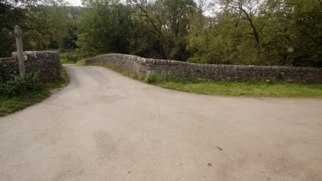 tiro ancho de la carretera que atraviesa el puente de piedra en wetton mill