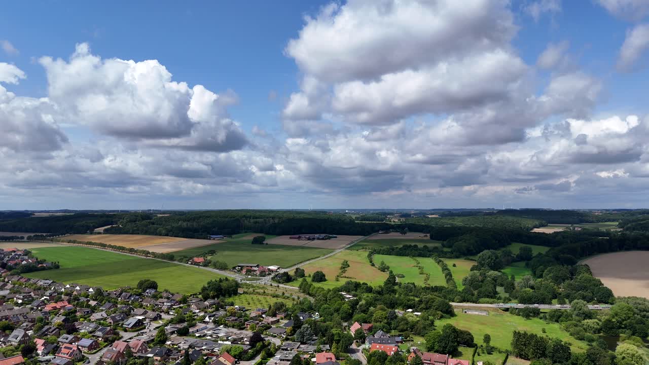 Scenic small town in USA with colored farm fields in countryside. Blue sky with dense clouds in summer. Slow drone dolly wide shot. Suburb area of neighborhood. Quaint and quiet scene