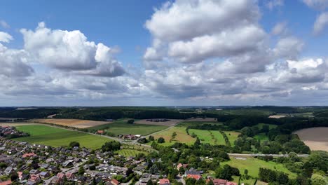 scenic small town in usa with colored farm fields in countryside. blue sky with dense clouds in summer. slow drone dolly wide shot. suburb area of neighborhood. quaint and quiet scene