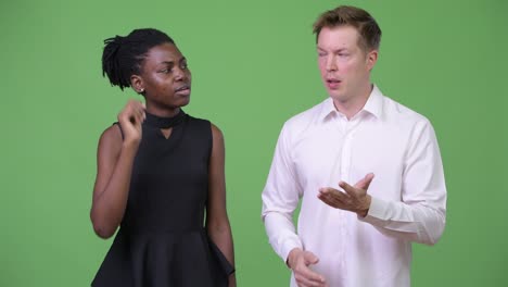 two young multi-ethnic business couple giving thumbs down together