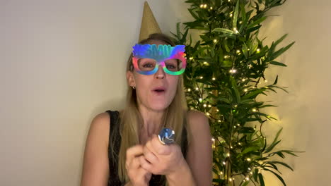 mujer joven en cuenta regresiva de videollamada para año nuevo y celebrando con un popper de fiesta