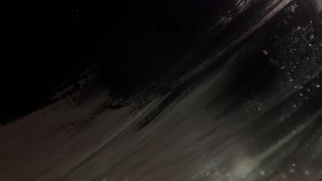 Abstract close-up of dark, textured surface with light reflections and shadow play