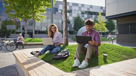 freelancer team working park together. smiling couple browsing laptop computer