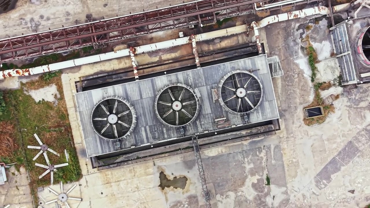 Industrial cooling system on a rooftop in an urban area showing fans and piping during daylight
