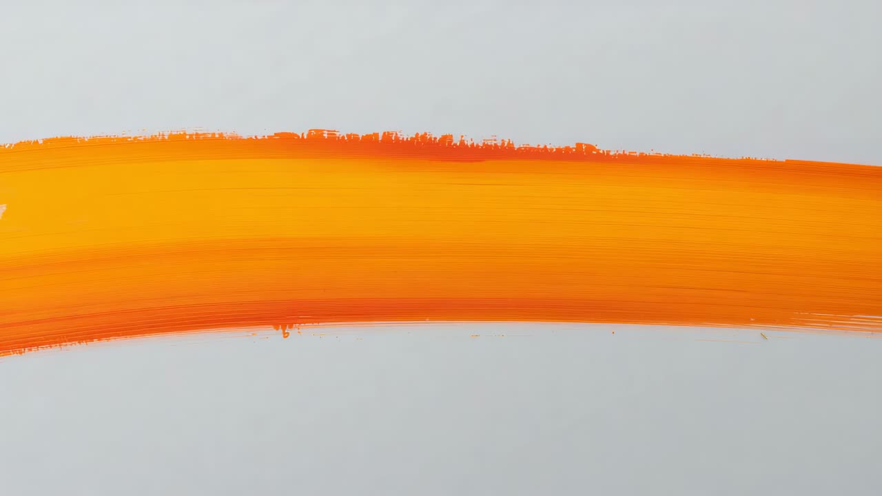 Assestamento dopo l'applicazione di un'ampia pennellata di vernice arancione che mostra un pigmento uniforme su un foglio chiaro, luce soffusa