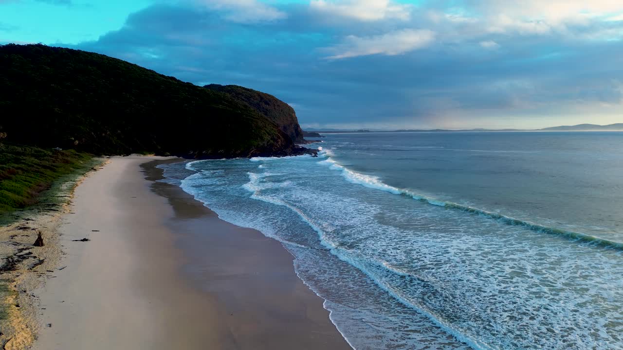 Drone aerial landscape of waves crashing onto sandy shoreline at Elizabeth Beach with headland coastline bushland trees at Booti Booti National Park in Pacific Palms Australia travel hiking tourism