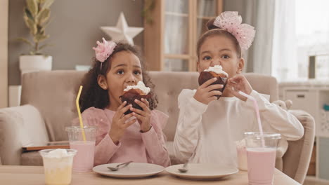 little sisters eating cupcakes at home