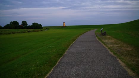 Red-yellow-lighthouse-in-the-north-of-Germany-on-a-dune-with-grass-in-the-evening