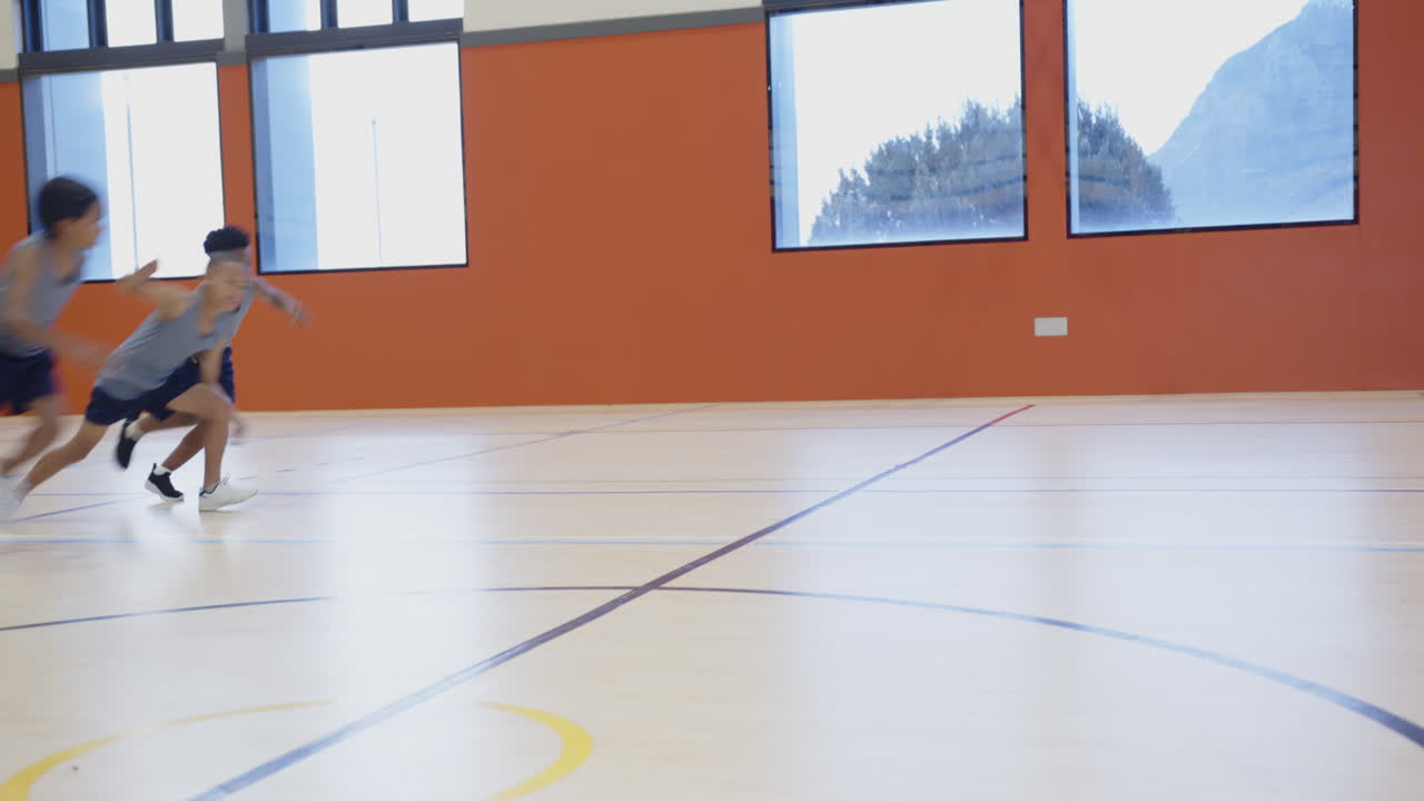 Playing basketball in school gymnasium, boys dribbling and practicing together