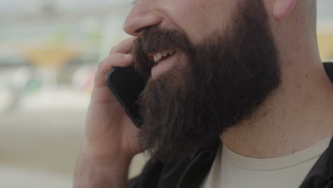 una foto recortada de una cara masculina hablando en un teléfono inteligente.