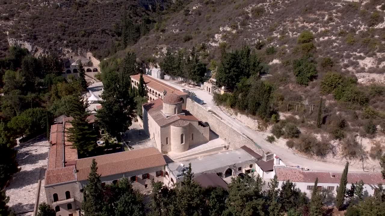 A stunning view showcases an ancient monastery nestled in the hills, surrounded by lush greenery and historic buildings. Discover the beauty and tranquility of this sacred site