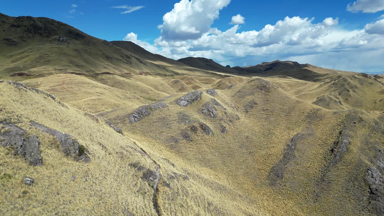Cinematic drone flight above the Andes in Peru. Pockets of sunlight sweep across green and gold mountain slopes in breathtaking contrast