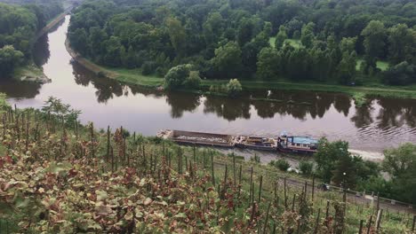 a tugboat pushes a barge carrying heavy stones upriver