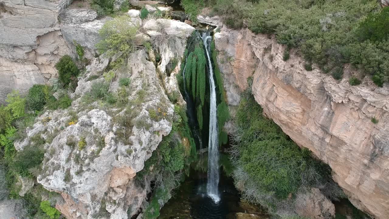 vistas aéreas de una cascada con una cueva y un edificio antiguo en cataluña, españa