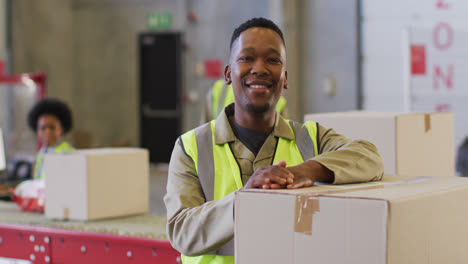 portrait of african american male worker wearing safety suit and smiling in warehouse