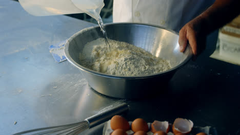 male chef pouring water in flour 4k