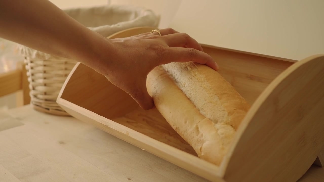 Hand Taking Fresh Loaf of Bread from Wooden Bread Box