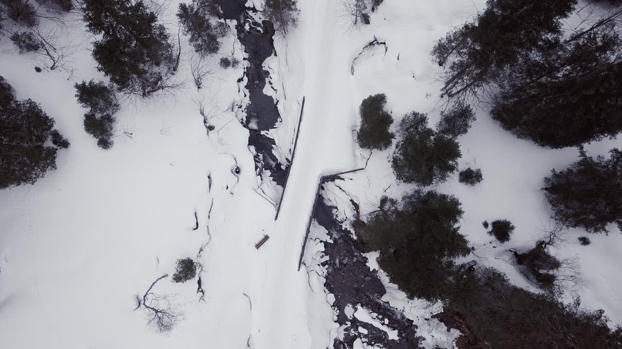 vista aérea hacia abajo en un pequeño puente sobre un arroyo en un valle nevado en los alpes, kleinwalsertal, austria