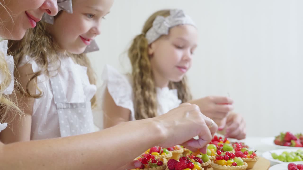 Mother and daughters baking fruit tartlets together