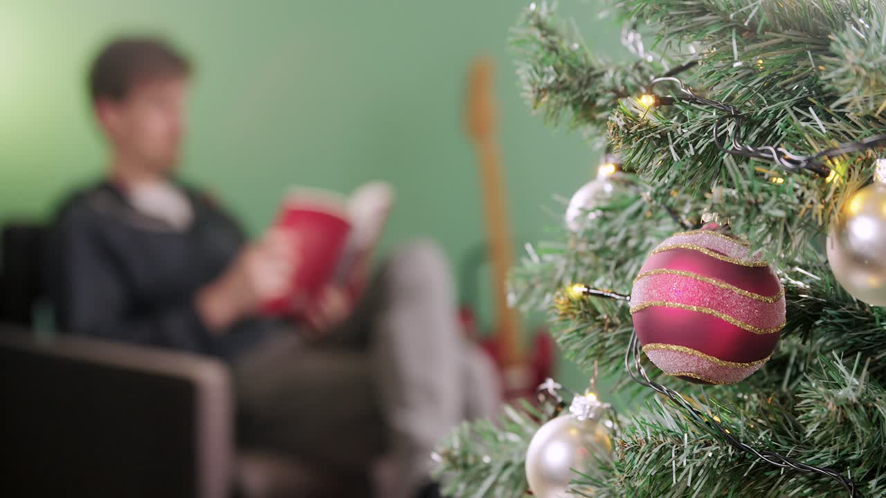 el hombre se relaja con un libro en la mañana de navidad con un árbol de navidad en primer plano