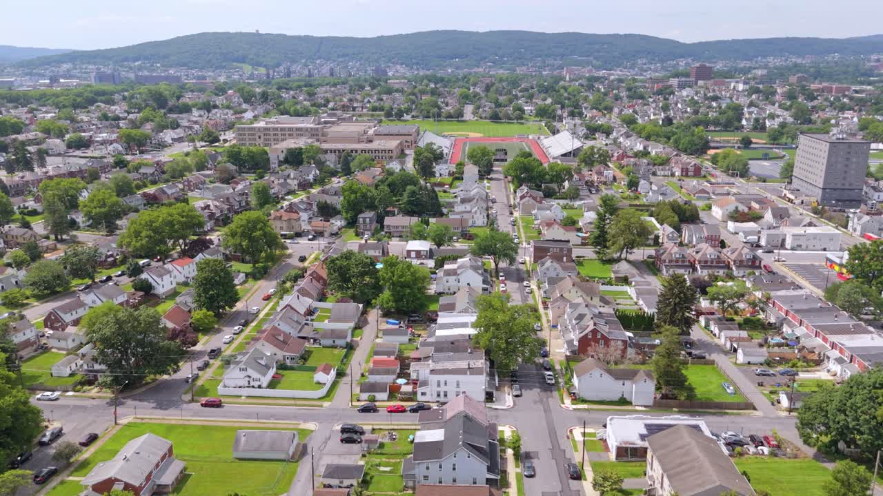 Residential neighborhoods in Bethlehem, PA with visible grid streets, green trees, and hills in background. Dolly in aerial